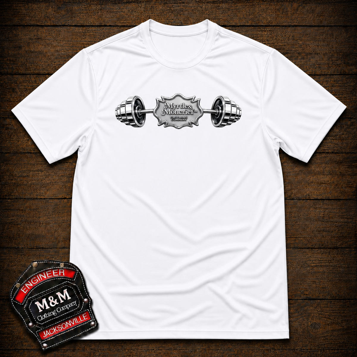 A white short-sleeve crewneck t-shirt with a black and silver barbell graphic on the chest. The graphic features a central badge with the text 'M&H Motorsports' and 'Jacksonville'.