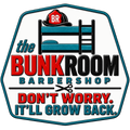 A hexagonal logo-style graphic for The Bunk Room Barbershop on a black background. The design shows a bunk bed with a red fire helmet on top, teal and black lettering reading 'the BUNK ROOM BARBERSHOP,' scissors in the center, and the phrase 'DON'T WORRY.