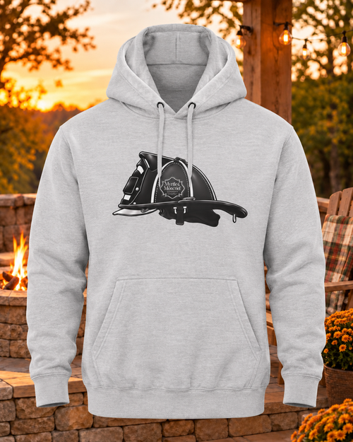 A light heather gray pullover hoodie with a black and white graphic of a firefighter helmet on the chest, displayed against an outdoor patio background at sunset.