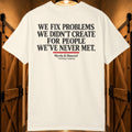 An off-white short-sleeve t-shirt with 'WE FIX PROBLEMS WE DIDN'T CREATE FOR PEOPLE WE'VE NEVER MET.' printed in black text on the back, displayed against a rustic wooden door background.