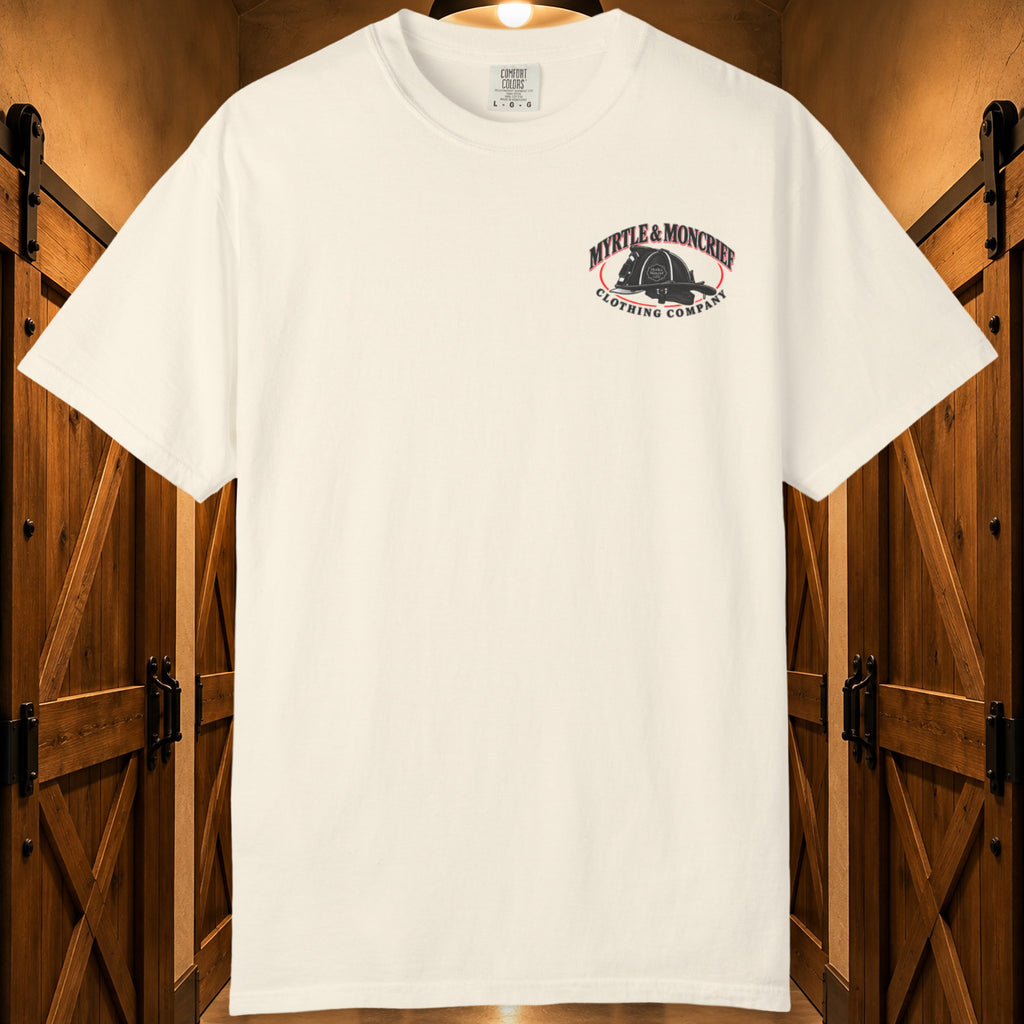An off-white short-sleeve t-shirt with a 'Myrtle & Moncrief Clothing Company' logo printed on the left chest, displayed against a rustic wooden door background.